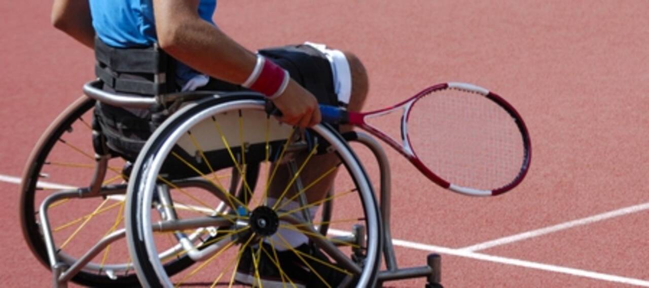 Photo d'un homme en fauteuil roulant qui tient une raquette de tennis