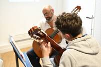Photo d'un professeur et son élève jouant de la guitare