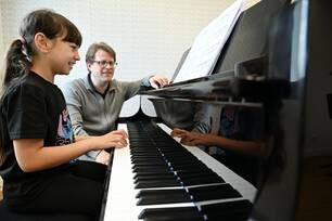 Photo d'un professeur avec élève jouant du piano